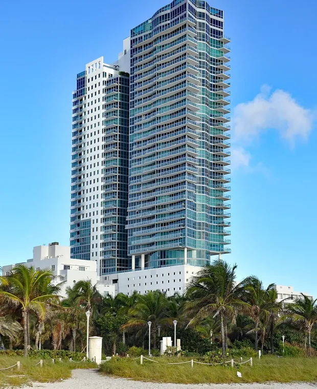 Torre residencial frente al mar y palmeras en Miami Beach